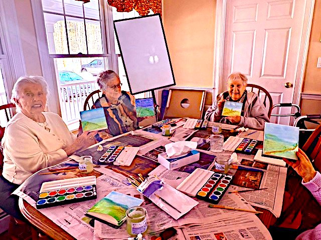Elizabeth Calsey House residents displaying watercolor paintings around a table